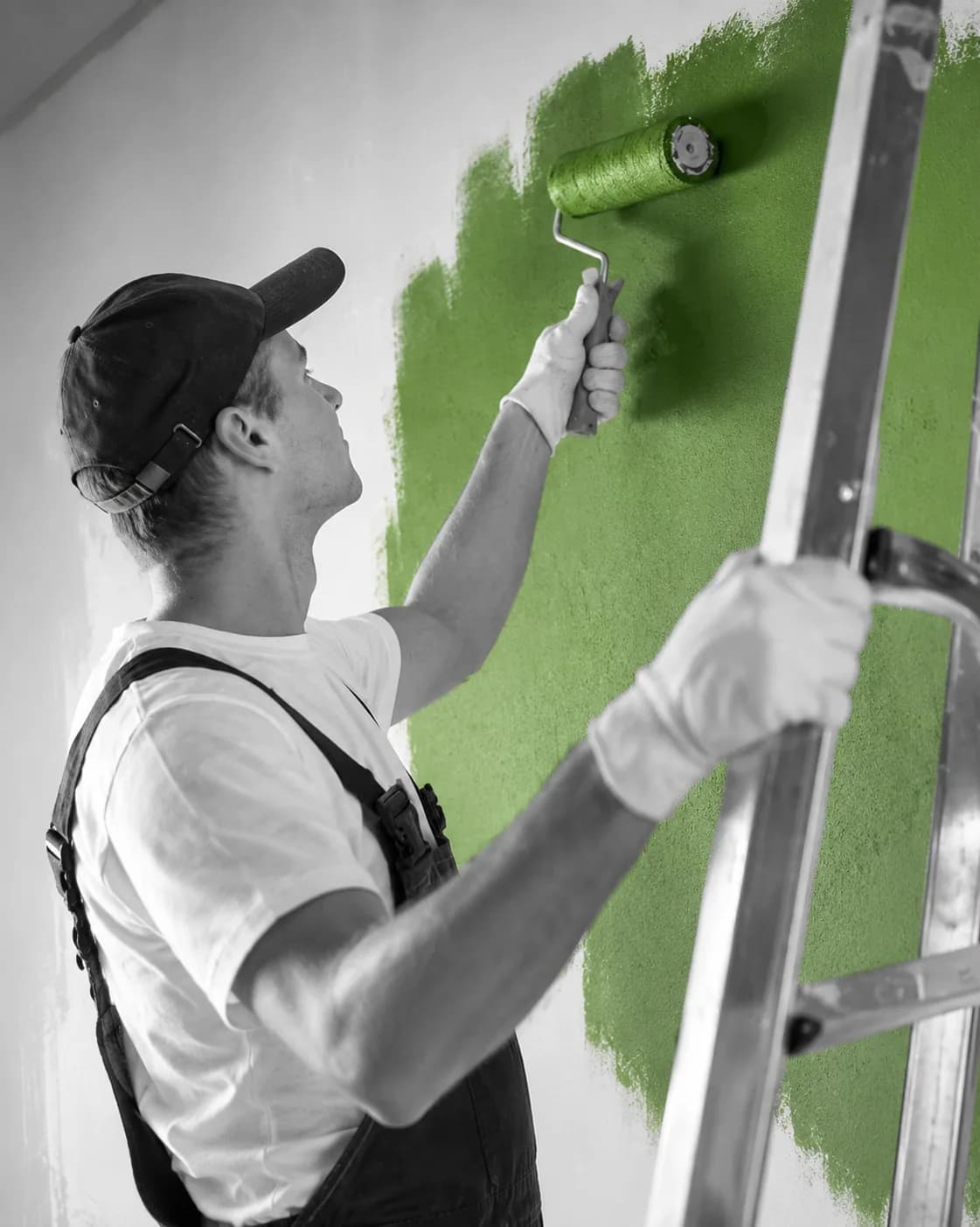 Painter on a ladder rolling green paint onto a wall